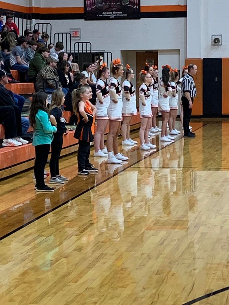 cheer leaders lined up in order from youngest to oldest in a gymnasium